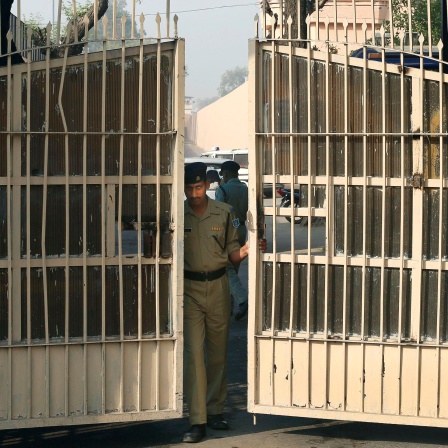 In indischer Polizist bereitet die Schließung des Tors des Tihar-Gefängnisses im indischen Nue delhi vor. Die in heller Farbe gestrichenen Flügel sind bereits fast geschlossen. 