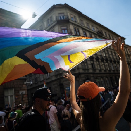 Eine Teilnehmerin hält bei einer Parade in Budapest eine Pride-Flagge in die Höhe.
