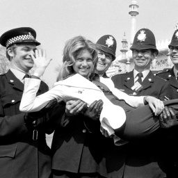 Olivia Newton-John posiert mit Polizisten in Brighton, während der Probe zum ESC 1974