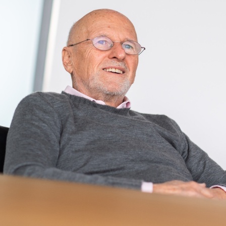 Der Unternehmer Dirk Rossmann sitzt an einem Tisch