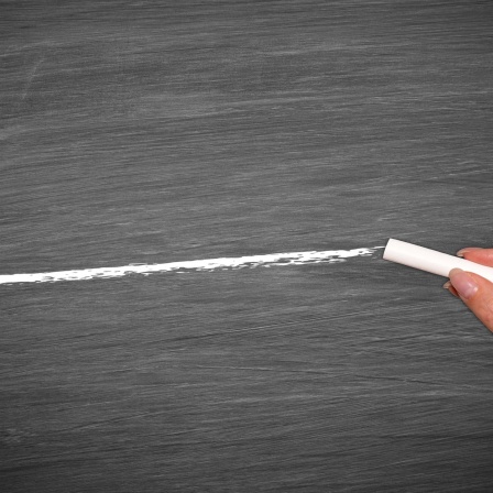 Hand with chalk drawing white line on empty chalkboard model released, Symbolfoto.