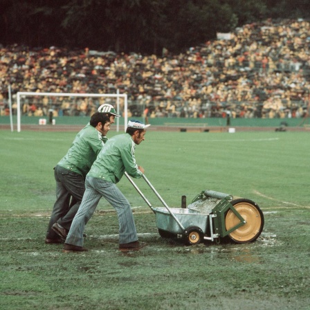 Drei Männer mit einer "Wasserkehrmaschine" beim Spiel Deutschland gegen Polen bei der WM 1974 im Frankfurter Waldstadion