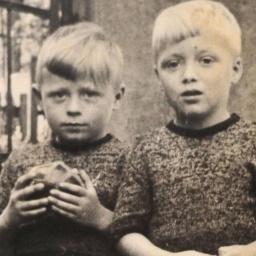 Eine alte Fotografie zweier Kinder. Eines hält einen Ball in der Hand.