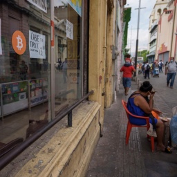 Ein Zeichen für die Zahlungsmöglichkeit mit Bitcoin ist an der Fensterscheibe eines kleinen Straßengeschäfts angebracht. 