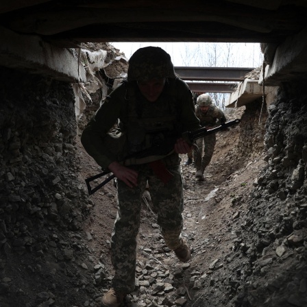 Ukrainische Soldaten gehen durch einen Tunnel an der Frontlinie in Luhansk.
      