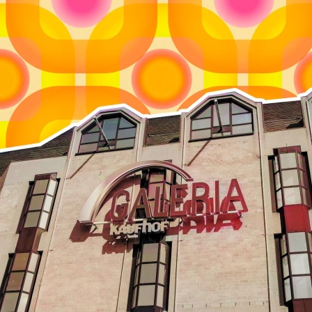 Ein Foto der Fassade von Galeria in Bonn. Die Fassade ist von unten fotografiert, so dass man schräg hoch zu den Lettern des Firmennamens schaut. Die Filiale ist vor einen Hintergrund gelegt, der an eine Retro-Tapete aus den 70ern erinnert.