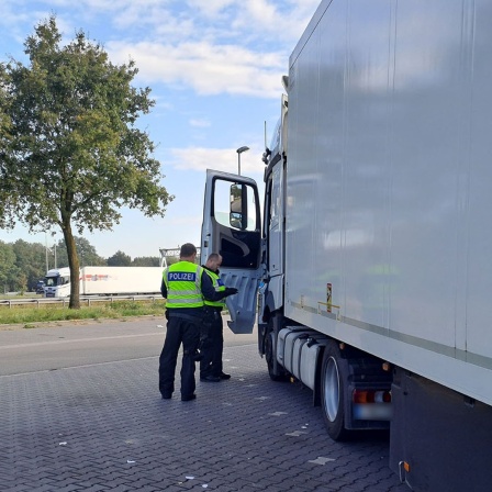 Polizeibeamte kontrollieren einen Lkw an der niederländischen Grenze.