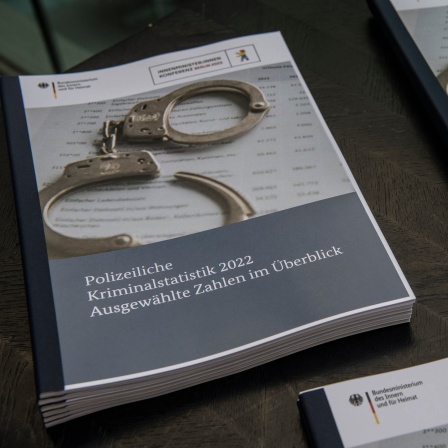 Der Bericht der Polizeilichen Kriminalstatistik 2022 liegt zusammen mit Handschellen auf einem Tisch