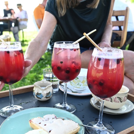 Eine Frau greift auf dem Hochwart auf der Insel Reichenau nach ihrem alkoholfreien Cocktail