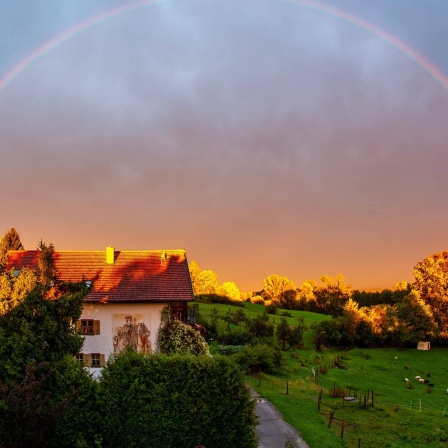 Nach ergiebigem Regen zeigt sich in der Abendsonne ein Regenbogen über dem Staffelsee bei Murnau