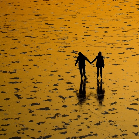 Zwei Menschen halten sich an den Händen, während sie auf dem zugefrorenen Moskauer Kanal Schlittschuh laufen.