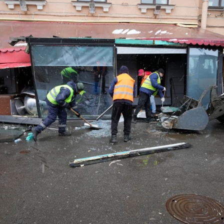Vor einem Café in St. Petersburg in Russland werden nach einer Bomben-Explosion Trümmer und Scherben beseitigt