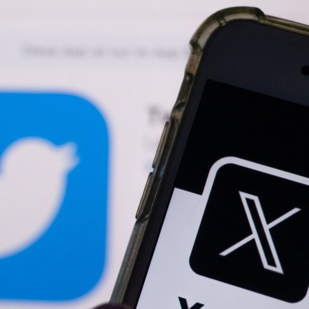 Der weiße Buchstabe X auf schwarzem Hintergrund auf einem Smartphone, im Hintergrund das bisherige Logo des Kurznachrichten-Dienstes Twitter 