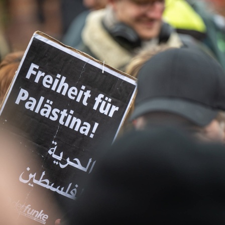 Proteste von Studierenden für Palästina - ein Mann hält ein Plakat hoch
