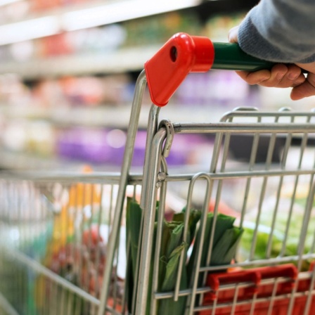 Ein Mann schiebt einen Einkaufswagen durch den Supermarkt. 