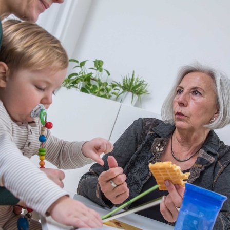 Oma hält dem ENkelkind eine Waffel hin und guckt grimmig
