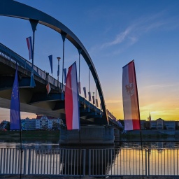 Fahnen wehen im Wind zum Sonnenaufgang vor der Stadtbrücke über den Grenzfluss Oder zwischen Frankfurt (Oder) und dem polnischen Slubice. 