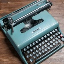 Eine alte Olivetti-Schreibmaschine steht auf einem Holztisch.