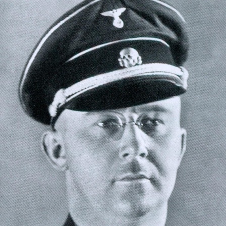 Ein Mann in SS-Uniform mit Brille und Schnauzbart.