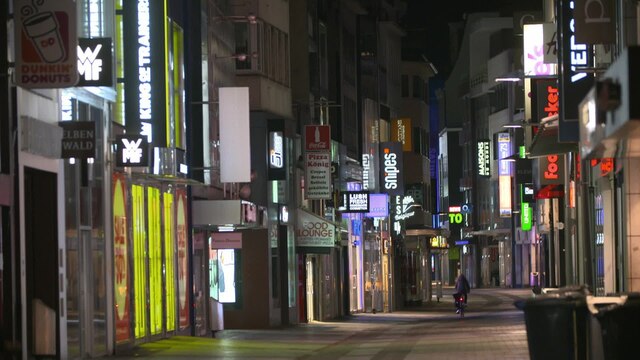 Das Bild zeigt eine beleuchtete Einkaufsstraße bei Nacht.
