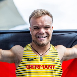 Kugekstoßer und Olympiasportler Niko Kappel im Deutschlandtrikot. Er hält eine Deutschlandfahne hoch.