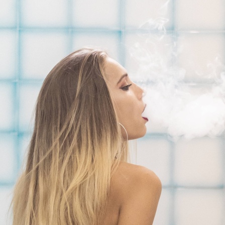 Eine Frau sitzt auf der Badewanne und raucht eine Wasserpfeife