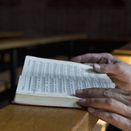 Hände auf Gesangbuch auf Kirchenbank