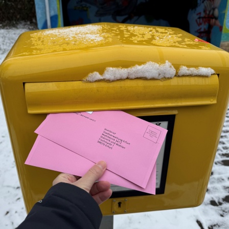 Die Unterlagen für die Briefwahl zur Bundestagswahl steckt eine Frau in Erfurt in einen Briefkasten