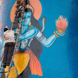 Ein Maler bei der Fertigstellung eines Bildes von Lord Shiva an den heiligen Stufen von Varanasi, Ganges, Indien.