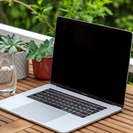 Homeoffice mit Laptop, Apple MacBook Pro und iPhone X am Schreibtisch, mit schwarzem Bildschirm.