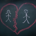 Ein zerbrochenes Herz mit zwei Menschen darin ist mit Kreide auf eine schwarze Tafel gemalt.