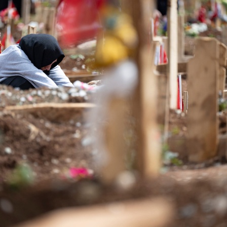 Weinend sitzt eine junge Frau auf einem Friedhof außerhalb der Metropole Kahramanmaras am Grab ihrer Schwestern, die bei dem Erdbeben im Februar ums Leben gekommen waren.