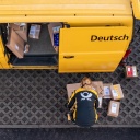 Eine Mitarbeiterin von der Deutschen Post DHL belädt ihr Fahrzeug