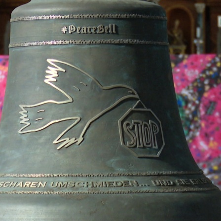 Glocke mit Friedenssymbolen in einer Kirche. 