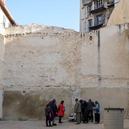 Menschen stehen bei einer Gedenkveranstaltung für die Opfer des Hauseinsturzes in Marseille in der Rue d'Aubagne an dem Platz, wo einmal zwei Häuser waren.