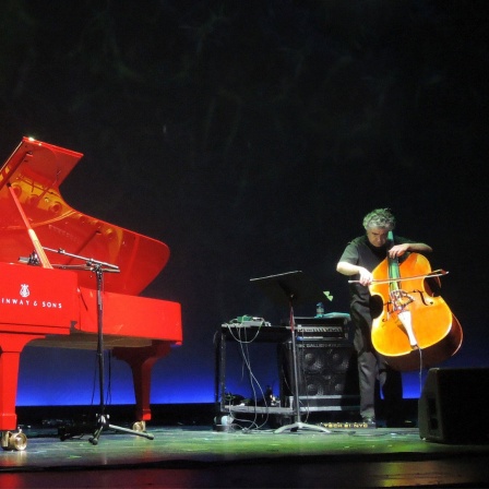 Ein Mann an einem Flügel und ein Mann mit einem Kontrabass musizieren auf einer Bühne.