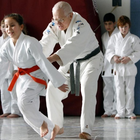 Eine Schülerin zieht während des Judo Unterrichts ihren Lehrer über die Judomatte