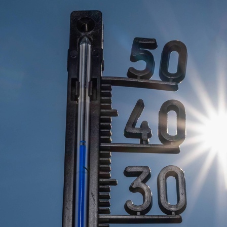 Ein Thermometer zeigt heiße Temperaturen an, im Hintergrund die gleißende Sonne