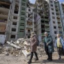 Drei Frauen stehen vor einem zerbombten Wohn-Hochhaus in Chernihiv, Ukraine 
