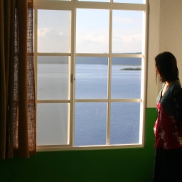 Eine Frau steht allein am Fenster.