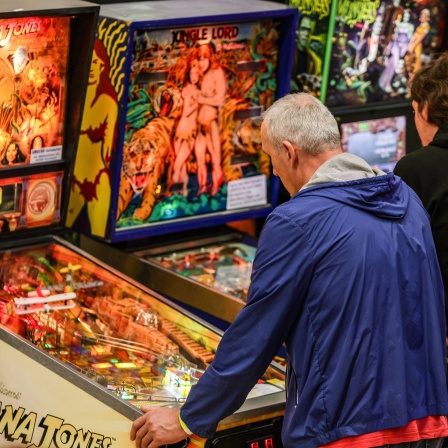 Teilnehmer stehen am ersten Turniertag bei der Pinball Convention mit offener Deutscher Flippermeisterschaft an Flippergeräten