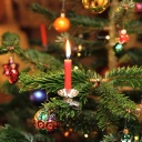 Kerzen brennen in einem Wohnzimmer an einem festlich geschmückten Weihnachtsbaum.