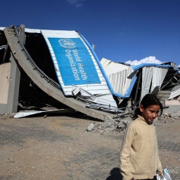 Zerstörtes WHO-Gebäude und Flüchtlingskind im Gazastreifen (Bild: IMAGO/NurPhoto/Majdi Fathi)