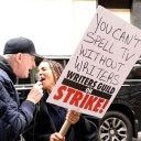 Ein Mann und eine Frau demonstrieten. Die Frau hält ein Plakat hoch, auf dem steht "You can't spell TV without writers" - auf deutsch "Du kannst Fernsehen nicht buchstabieren ohne Drehbuchautoren" 