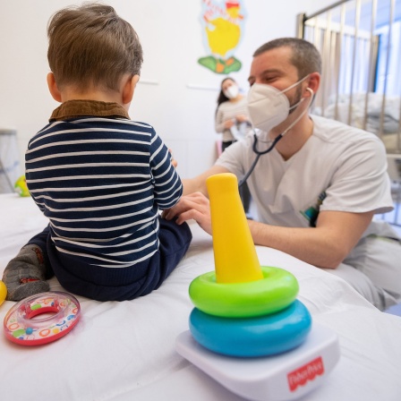 Ein Arzt untersucht in einer Kinderklinik ein Kind.