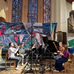 Ein Musikensemble spielt im von Stoffen verhüllten Innenraum der Bonner Kreuzkirche