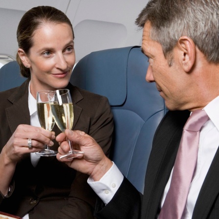 Ein Paar stößt mit Sekt im Flugzeug an