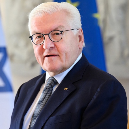 Bundespräsident Frank-Walter Steinmeier steht bei einer Veranstaltung vor einer israelischen, einer europäischen und einer deutschen Flagge.
