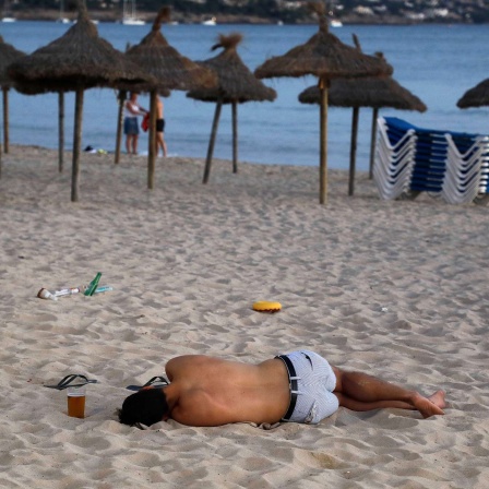 Ein junger Mann schläft am Strand von Arenal auf Mallorca. 