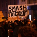Eine Teilnehmerin an der Demonstration linker Gruppen unter dem Slogan "For The Destruction of Patriarchy" hält in der Nähe vom Alexanderplatz ein Plakat mit der Aufschrift "Smash Patriarchy" hoch.